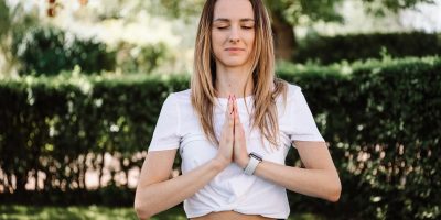 A serene moment of a woman practicing yoga with namaste pose outdoors, embracing mindfulness.