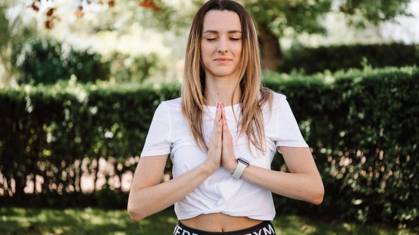A serene moment of a woman practicing yoga with namaste pose outdoors, embracing mindfulness.